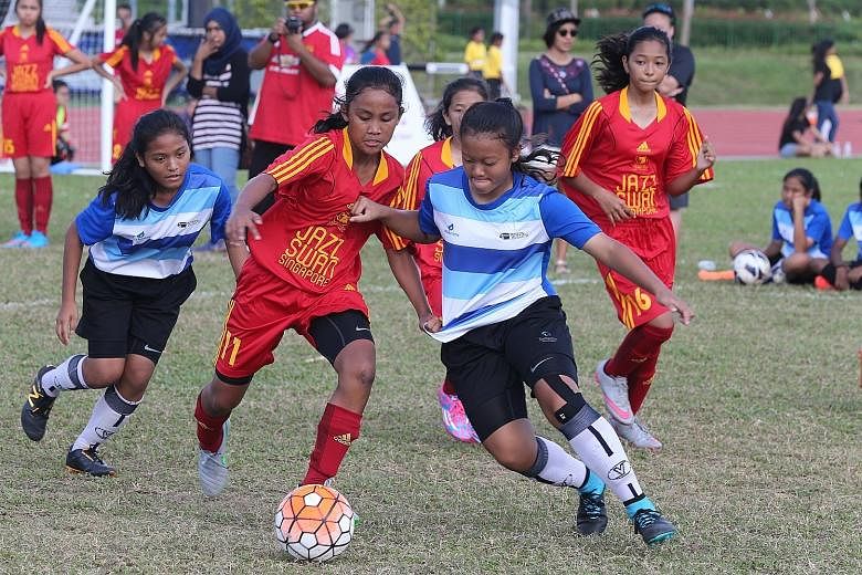 Furious action during a tournament for girls at the Women's Football Day in Kallang yesterday.