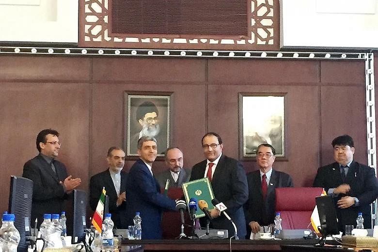 Mr Iswaran (centre, holding documents) and Dr Tayyebnia after signing the bilateral treaty yesterday.