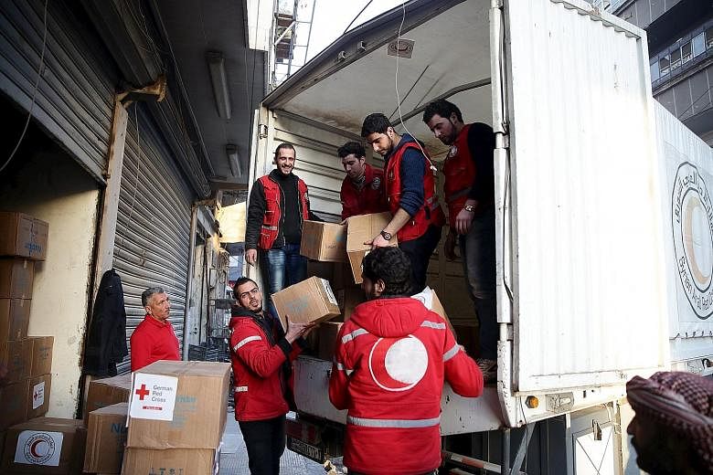 Red Crescent members unload aid boxes in the rebel-held city of Douma, a suburb of Damascus. The UN hopes to take advantage of the relative calm of the ceasefire to distribute supplies to 154,000 living in besieged areas over the next five days.