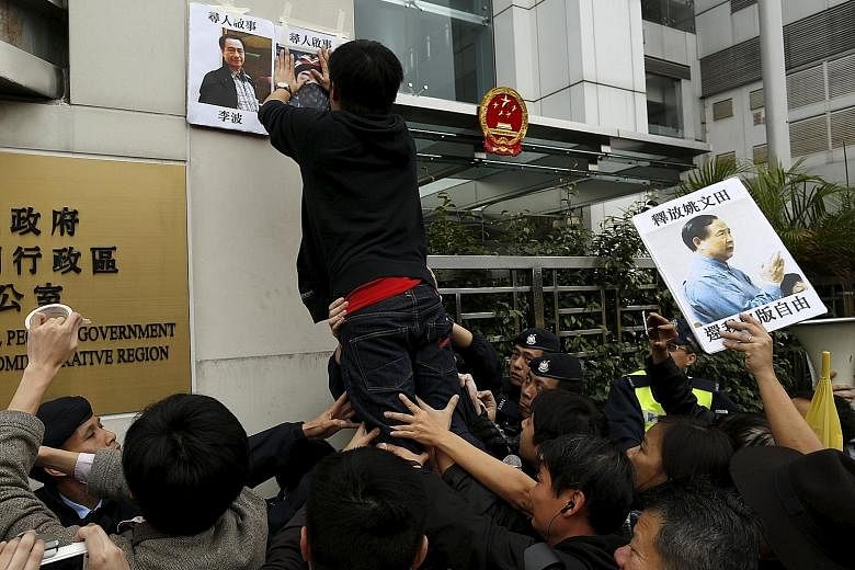 A pro-democracy demonstrator posting portraits of Hong Kong bookseller Lee Bo (top left) and Mighty Current publishing house's general manager Lui Por outside the Chinese liaison office in Hong Kong on Jan 3, during a protest to call for an investiga