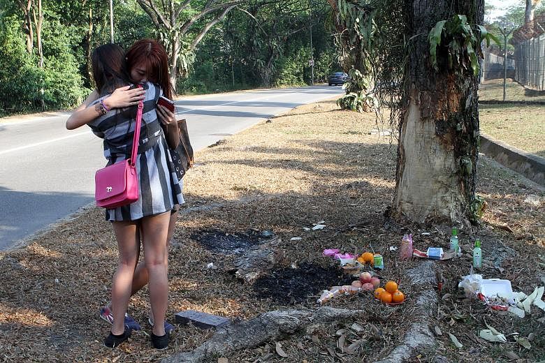 Friends of Ms Lo at the site of the fatal car crash in Tampines. She and Ms Phoe were flung out of the rear seat of the car and killed when the vehicle skidded and slammed into a tree.