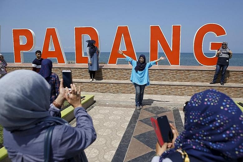 Visitors along the Sumatran coast posing for shots in front of the Indian Ocean yesterday, just a day after the magnitude 7.8 quake struck. It set off 11 aftershocks but, so far, there have been no reports of casualties or major damage.