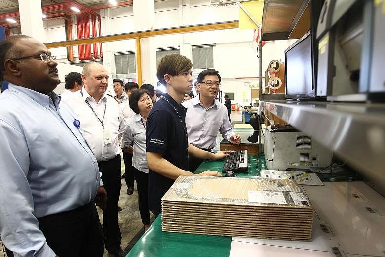 A worker at Pan Asia Logistics showing Mr Heng (right) how goods are being moved through a computerised process. Accompanying the minister are (from left) the firm's senior manager Sundaram Velosamy, executive chairman Christian Bischoff and chief ex
