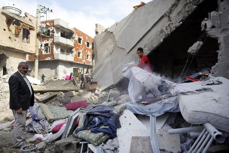 Kurdish people searching through rubble on the street on Thursday, the day after clashes between Turkish special forces and PKK militants broke out in south-east Cizre district in Sirnak, Turkey. 