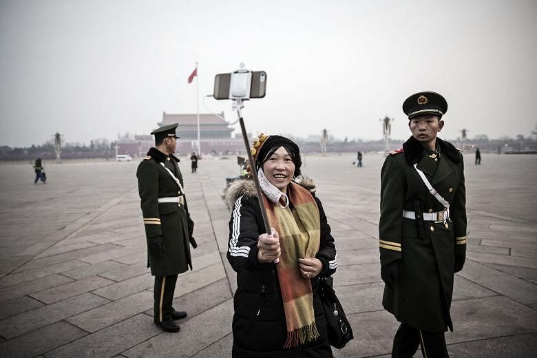 A visitor to Tiananmen Square on Thursday using a smartphone on a selfie stick to capture a shot with a paramilitary police officer after the daily flag-raising ceremony there. 