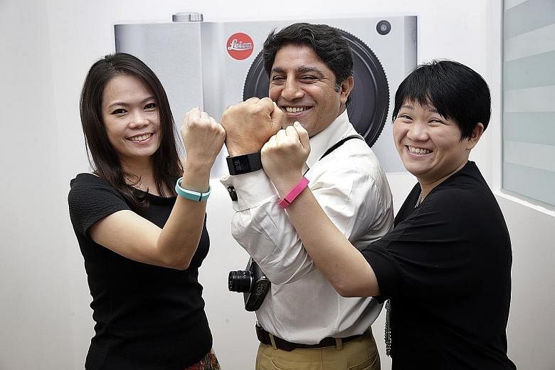 (From left) Finance executive Crystal Lim, 37, managing director Sunil Kaul, 47, and operations manager Sally Yeo, 34, at camera maker Leica, with their Fitbit fitness trackers. The data collected by Fitbit can be used to monitor staff welfare, and t