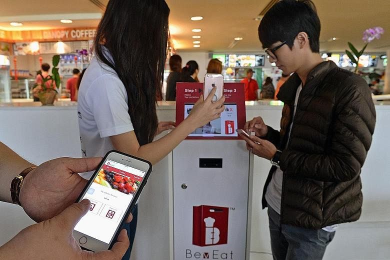 Ms Tham and Mr Sasaki trying out the cashless payment system being piloted at a cafeteria at Republic Polytechnic.