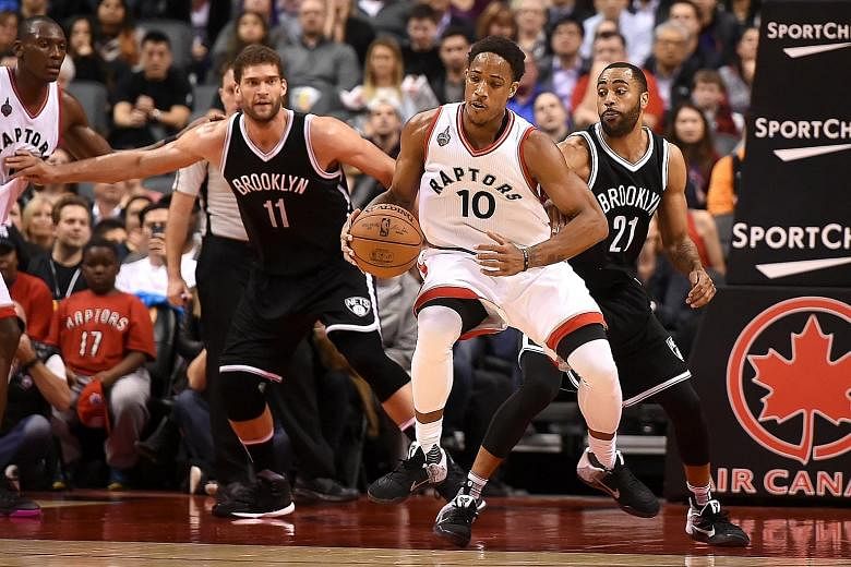Toronto Raptors guard DeMar DeRozan grabbing a loose ball in front of Brooklyn Nets centre Brook Lopez (left) and guard Wayne Ellington at Air Canada Centre. The Raptors won 104-99 after trailing by 16 points at half-time.