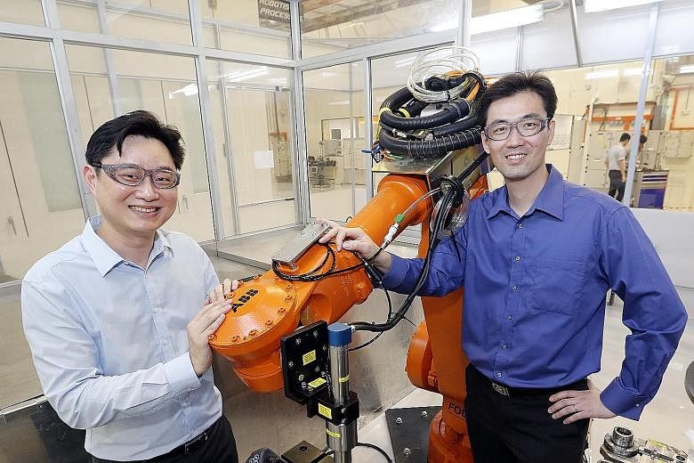 ARTC's Mr Ooi (left) and Sankei Eagle's Mr Siew with a manufacturing robot. Sankei Eagle worked with ARTC and aerospace firms to build a prototype to automate the masking process in application of coatings.