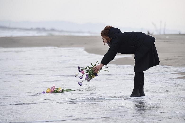 A woman laying flowers at sea yesterday in the city of Sendai, northern Japan, to remember the victims of the earthquake and tsunami that struck the country on March 11, 2011. Japan yesterday marked the fifth anniversary of the calamity that claimed 