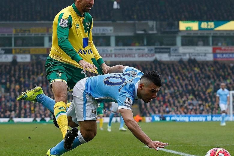 Manchester City forward Sergio Aguero (right) tumbling as he comes up against Norwich midfielder Gary O'Neil. Aguero was tightly marshalled by the home team.