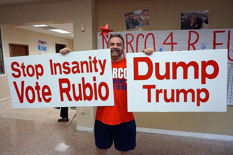 Mr Baez standing outside the early voting station at Coral Gable Library, giving out bumper stickers and fliers. With him is his wife, Teresa Mr Andrew Garcia, 58, a business owner, at the Marco Rubio campaign office in Miami.
