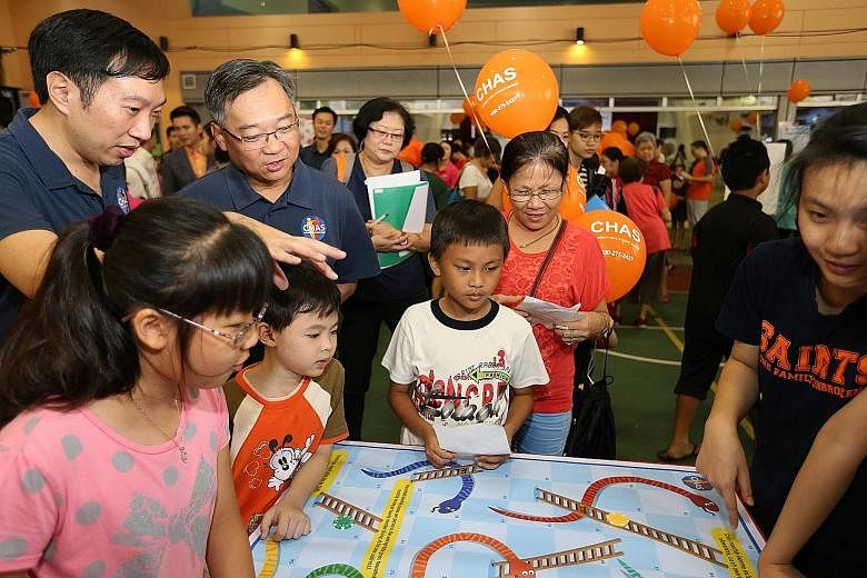 Visitors to the carnival at Choa Chu Kang Community Club yesterday having fun playing board games, while Health Minister Gan Kim Yong (second from left) looked on. Mr Gan said a family's regular GP can be a "trusted partner", adding: "As they know ou