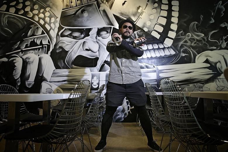 Mr Azlan, better known as Ceno2, has created several hundred graffiti artworks in Chicago and New York, and has also done numerous local pieces. He is pictured here with an artwork that he did for a local restaurant.