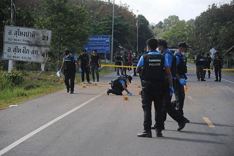 Thai bomb squad members inspecting the site of a roadside bomb attack on Sunday in the Cho-airong district of Narathiwat.