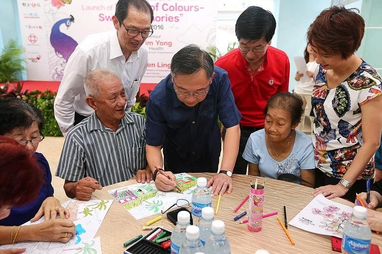 Mr Gan Kim Yong (centre) tries his hand at colouring with senior citizens at the launch of World Of Colours - Sweet Memories at Bukit Batok West yesterday. Looking on are (from left) Mr Seow Choke Meng, business consultant of SPH's Chinese Media Grou