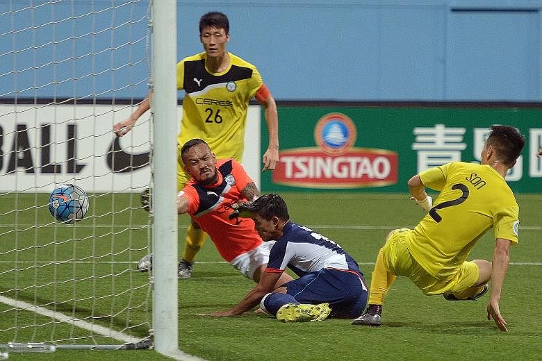 Tampines' Hafiz Abu Sujad bundling the ball home despite the vain attempts of defender Kim Sang Min (No. 26), goalkeeper Louie Michael Casas and defender Son Yong Chan (No.2) to keep it out.