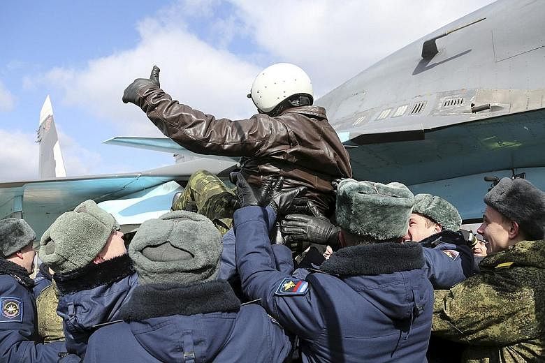 A Russian military pilot being greeted upon his return from Syria to a home airbase on Tuesday. Although President Putin has announced the withdrawal of troops from Syria, where Russian forces have been pounding rebels who are against President Assad