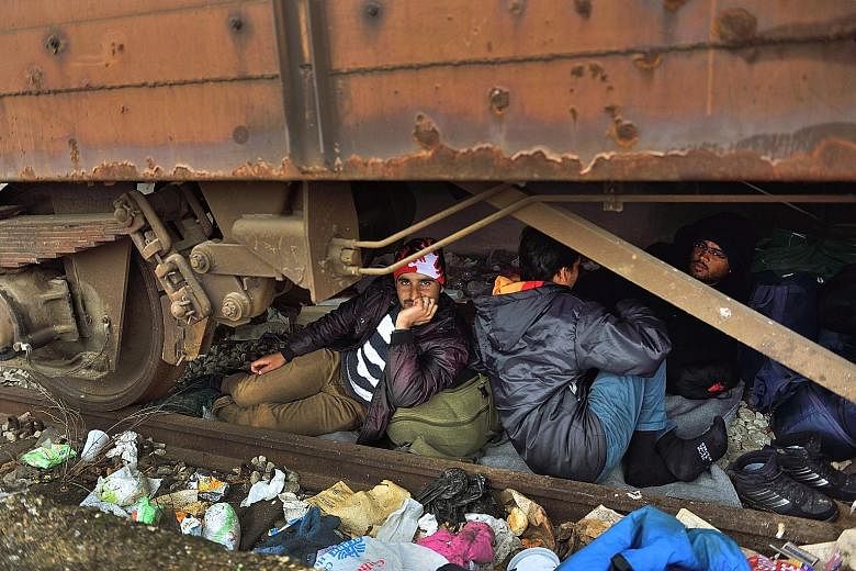Refugees taking shelter under a train carriage at a camp at the Greek- Macedonian border yesterday, where thousands of refugees and migrants are stranded