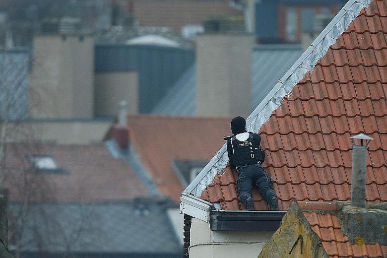 An officer on a rooftop during the police operation in Forest, Brussels, on Tuesday. The anti-terror raid was linked to the Paris attacks last November.