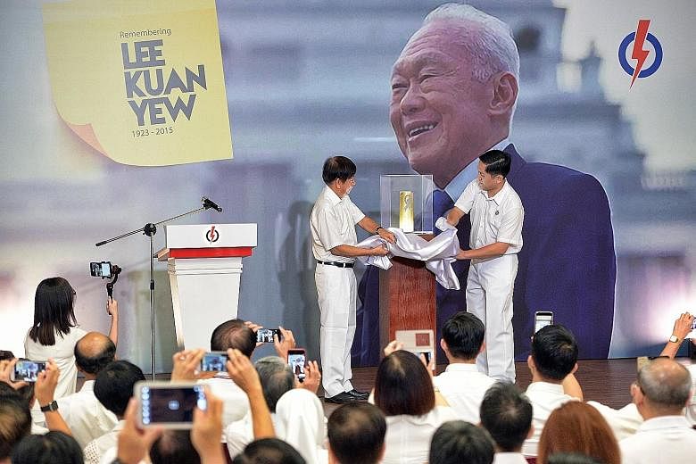 PAP chairman Khaw Boon Wan (far left) and PAP headquarters executive director Alex Yam unveiling the artillery shell casing from a 21-gun salute for Mr Lee's state funeral, which Prime Minister Lee Hsien Loong gave to the party.