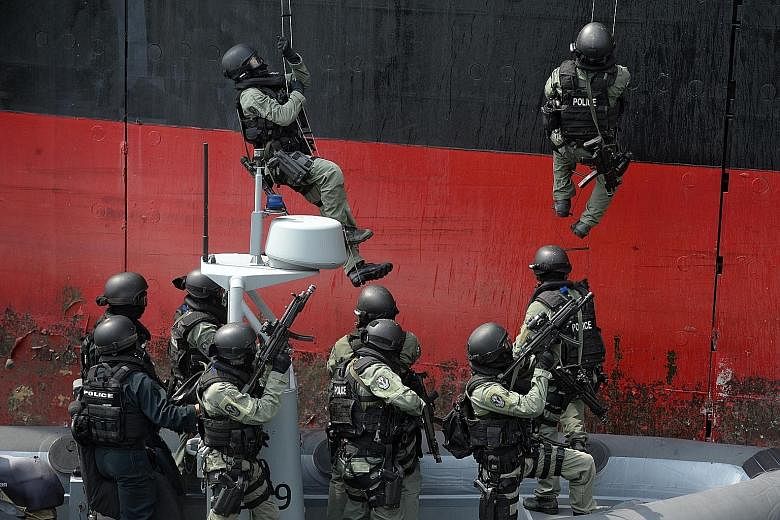 Members of the Singapore Police Force Special Tactics and Rescue Unit, supported by the Police Coast Guard Special Task Squadron, storming a vessel during a showcase of their counter-terrorism and maritime security measures, at the Police Coast Guard