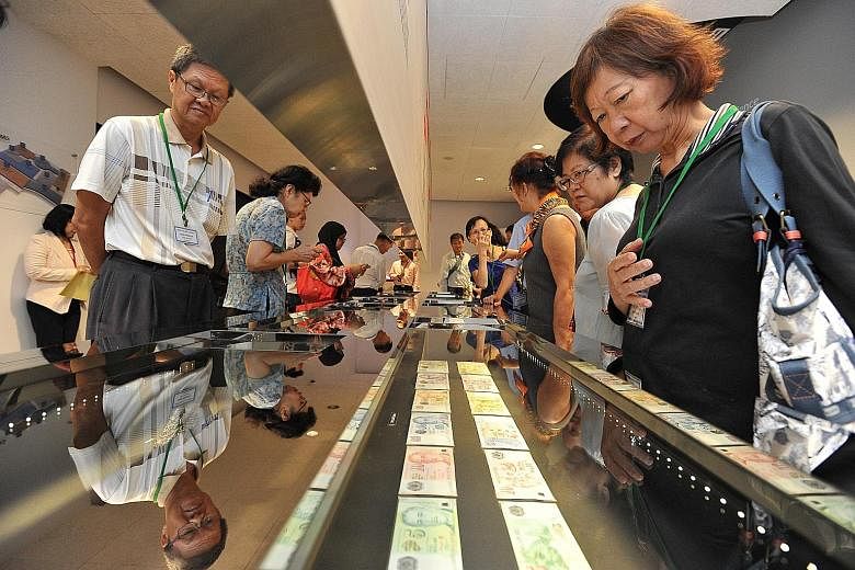 A stronger Singdollar against the greenback is a boon for Singapore tourists. (Above) Visitors viewing the currency notes and coins on display at the MAS Gallery.