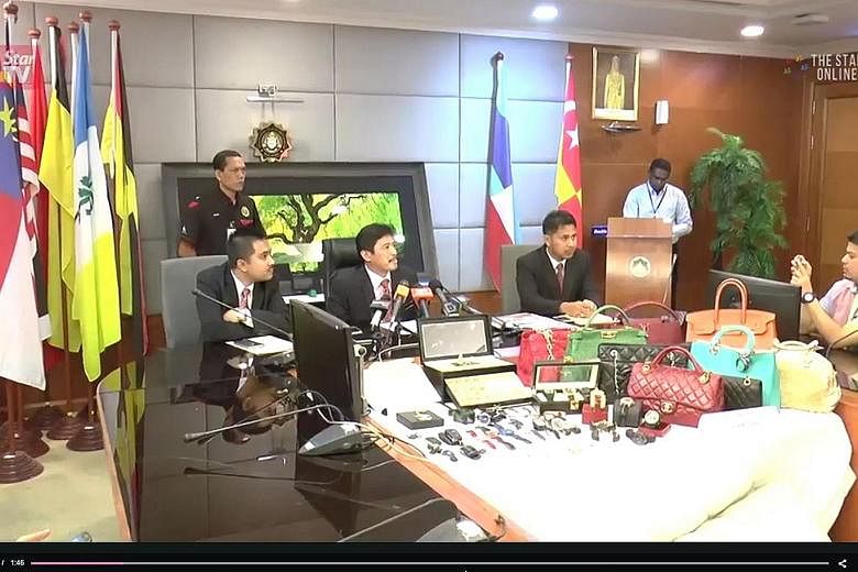 MACC officers displaying to the media some of the jewellery, luxury watches and brand-name handbags seized from the nine suspects.
