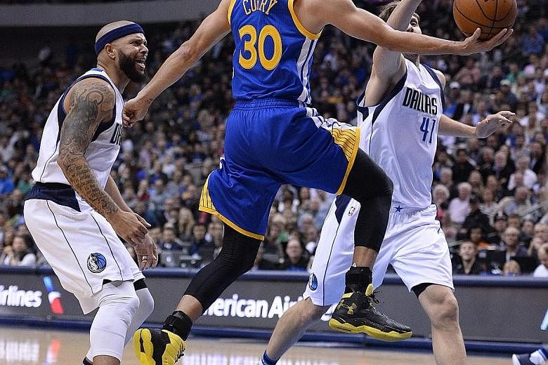 The Warriors' Stephen Curry going to the basket as the Mavs' Dirk Nowitzki tries to block him, with Deron Williams urging him on. Golden State won 130-112 and improved to 62-6.