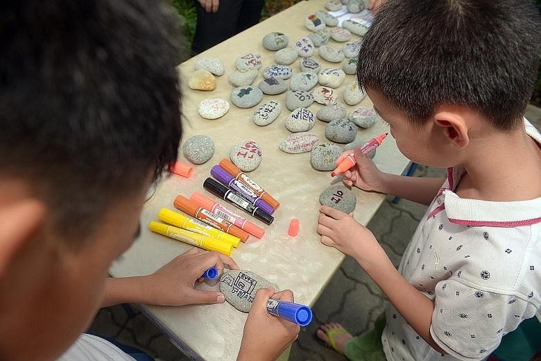 Six-year-old Wu Xing Hong (above, right) penning his hopes for Singapore on a pebble at the remembrance event in Tanjong Pagar yesterday. Over at Bishan-Ang Mo Kio Park (below), PM Lee and Mrs Lee joined residents in pledging their support, for Singa
