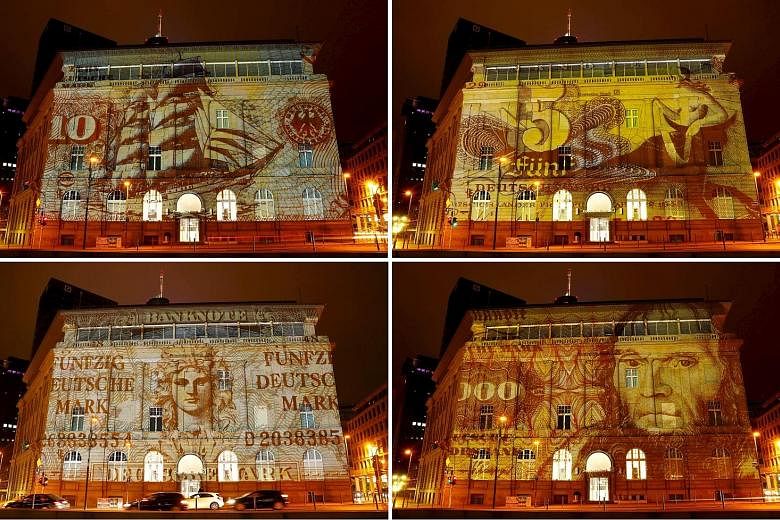 A branch of Deutsche Bank is illuminated with banknotes of Germany's former currency, the deutsche mark, for the "Luminale, light and building" event in Frankfurt.