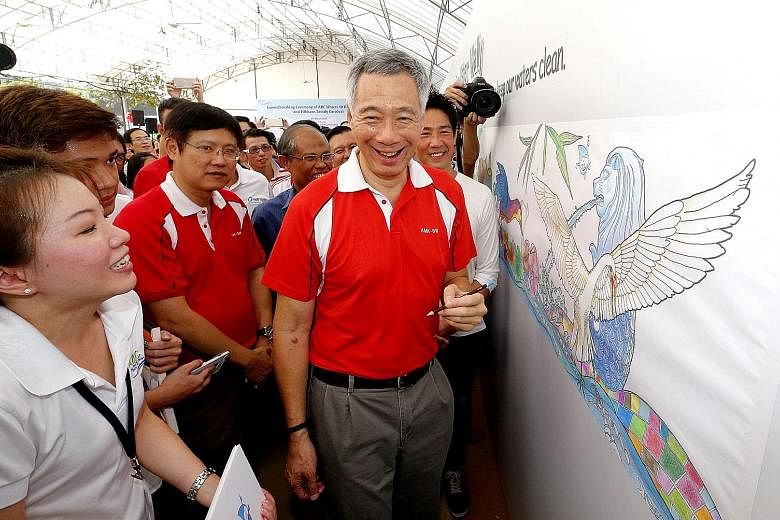 PM Lee colouring illustrations meant to inspire people to keep the waters clean during the ground-breaking ceremony for three waterway projects in Hougang yesterday.
