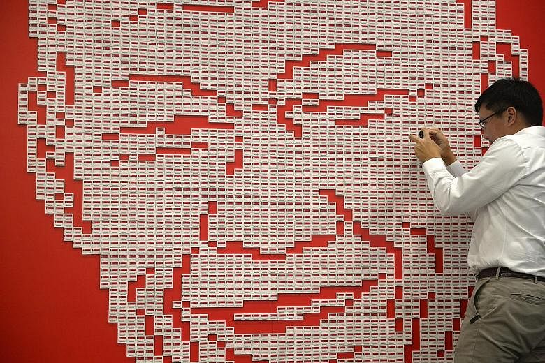 Mr Shaun Lee, nephew of the late Mr Lee Kuan Yew, taking a photo yesterday of the art installation made up of 4,877 Singapore flag erasers put together to form his uncle's image. The installation at The Red Box in Somerset Road was constructed by som
