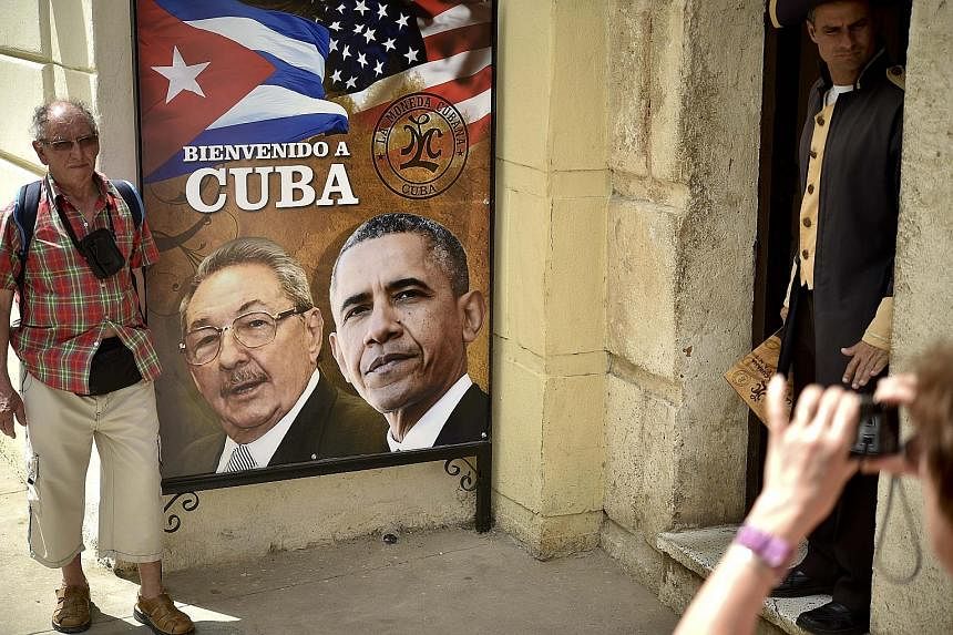A tourist in Havana posing with a poster carrying the images of Cuban President Raul Castro and his American counterpart Barack Obama on Saturday. Mr Obama arrived in Cuba yesterday.