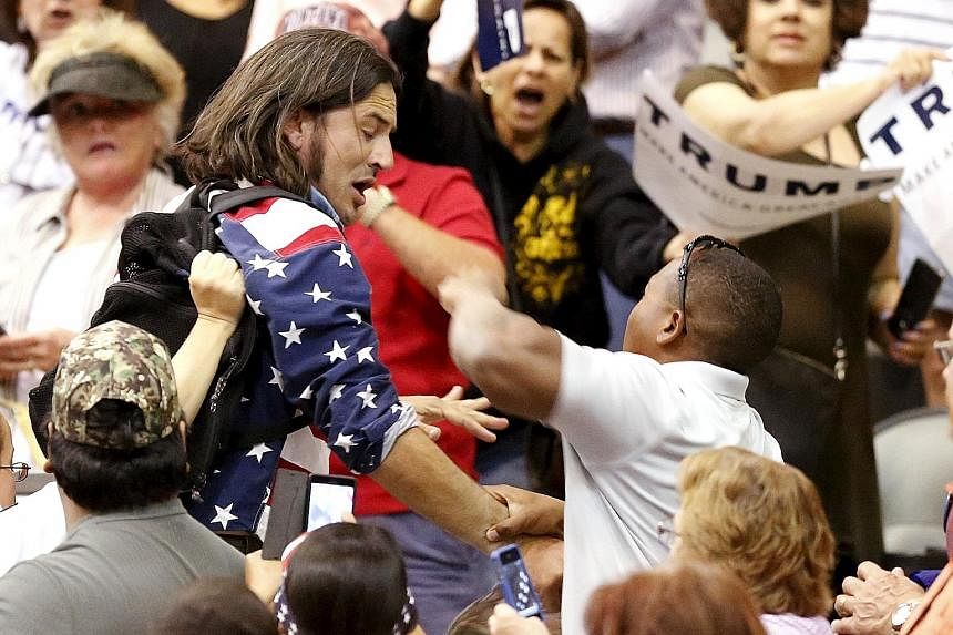 A protester (in blue) being attacked by Trump supporters while the billionaire candidate was giving a speech at a campaign event in Tucson, Arizona on Saturday.