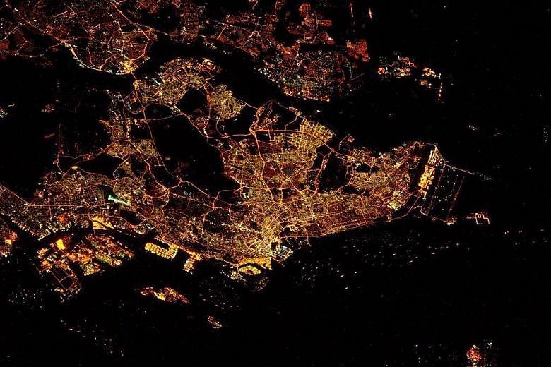Nasa astronaut Scott Kelly (right) turning over command of the ISS to Mr Tim Kopra (left) on Feb 29. (Right) The night image of Singapore captured by Mr Kopra last Saturday depicts the country as an intricate network of yellow lights.