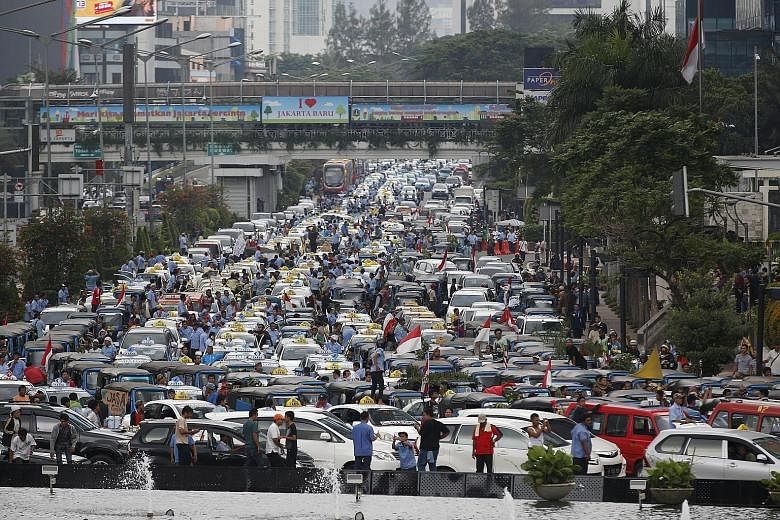 Taxi drivers protesting against ride-hailing app services on a main street in Jakarta yesterday. Many called for a ban on services like Uber and Grab, calling them "illegal" and said they halved the incomes of regular cabbies.