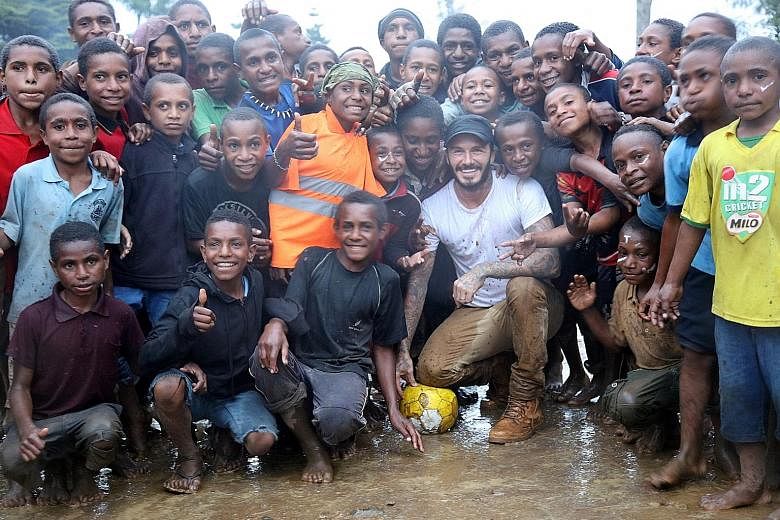 After playing football with students in Nepal, his face is covered with crimson paint, the national colour of Nepal. David Beckham poses with the children in Kumnga village (above) after an impromptu football match in the rain in Papua New Guinea, an