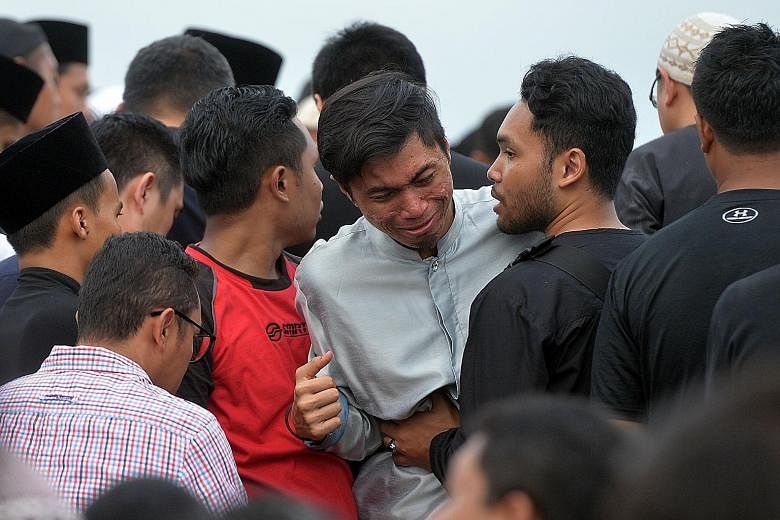 Mr Hatin (centre) grieving at the burial of his two SMRT colleagues at the Muslim cemetery in Lim Chu Kang yesterday.