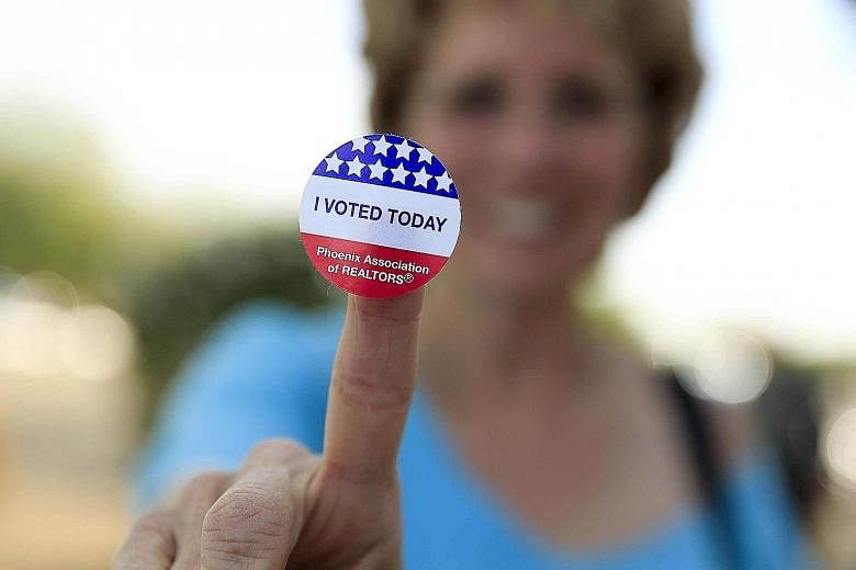 A woman showing off her voting sticker outside a polling site in Glendale, Arizona, on Tuesday. Democratic favourite Hillary Clinton now has 1,681 of the 2,383 delegates required to win the nomination, while Republican front runner Donald Trump's del