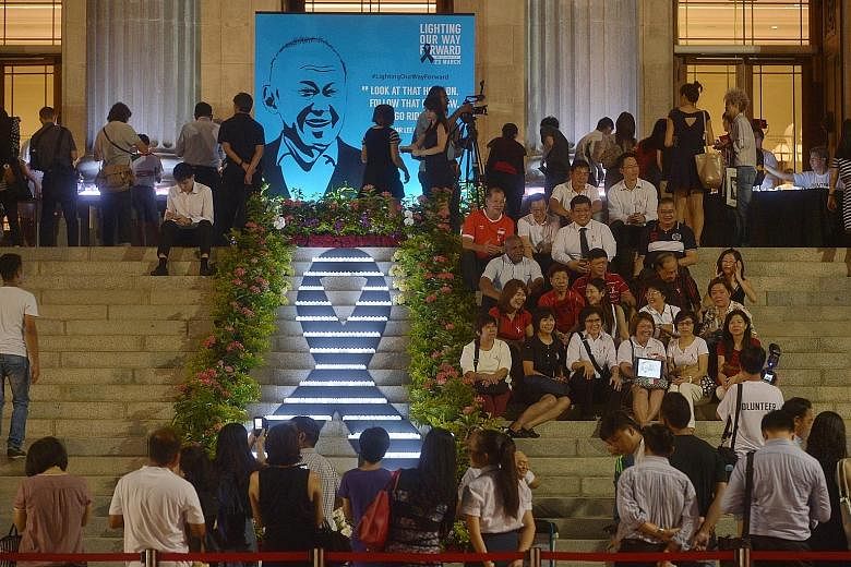 Volunteers and partners of the People's Association laying flowers at a remembrance site for Mr Lee at Istana Park yesterday. At the National Gallery, on the steps of the former City Hall, a group of volunteers formed an illuminated ribbon with elect