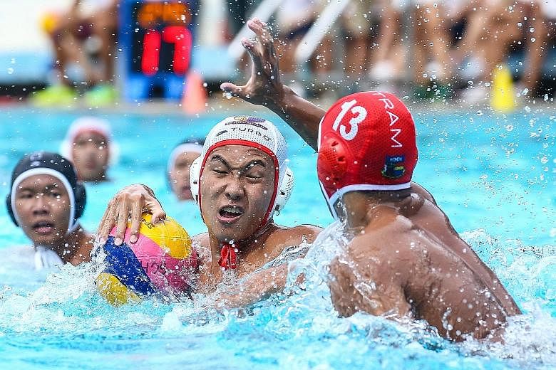 Chan Tze Kai of ACS(I) protecting the ball against Tan Zheng Yu of Outram during the B Division water polo final. Playing against their senior A Division boys in training helped build up ACS(I)'s confidence.