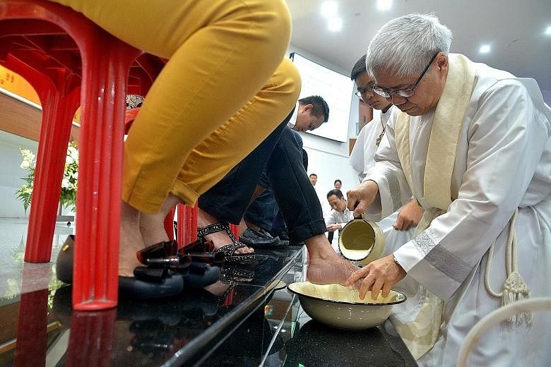 Catholic Archbishop William Goh washing the feet of one of 12 parishioners at the Church of the Holy Cross, as part of its annual Maundy Thursday mass. Half of them were women, a first this year following a new ruling issued by Pope Francis in Januar