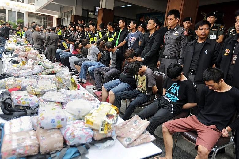 Malaysians alleged to be members of a drug-trafficking gang lined up next to bags of heroin and methamphetamine. They were arrested for trying to smuggle the drugs by train from Thailand into the Malaysian town of Butterworth.
