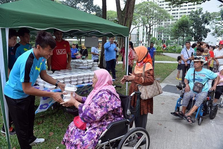 Home United FC player Sufianto Salleh helping to distribute packets of food to the elderly in Boon Lay Drive yesterday. The team players were acting in partnership with charity Free Food For All, which distributes halal meals to the elderly and under
