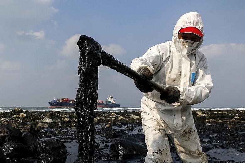 (Left) A worker collecting oil spilled from a container ship owned by T.S. Lines off Shimen, New Taipei City, Taiwan, yesterday. The 15,487-tonne ship ran aground in a storm about 300m from the shore while it was sailing from Hong Kong to Keelung Por
