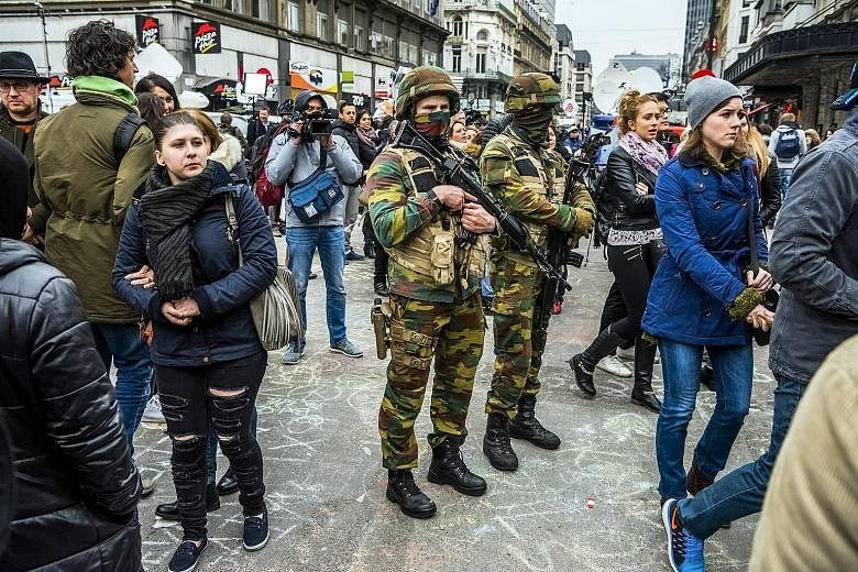 Soldiers standing guard as people pay respects to victims of Brussels' bombings, which killed at least 31 people and injured about 300 more. Belgian Interior Minister Jan Jambon had gone on radio one day earlier and warned that his country faced a "c
