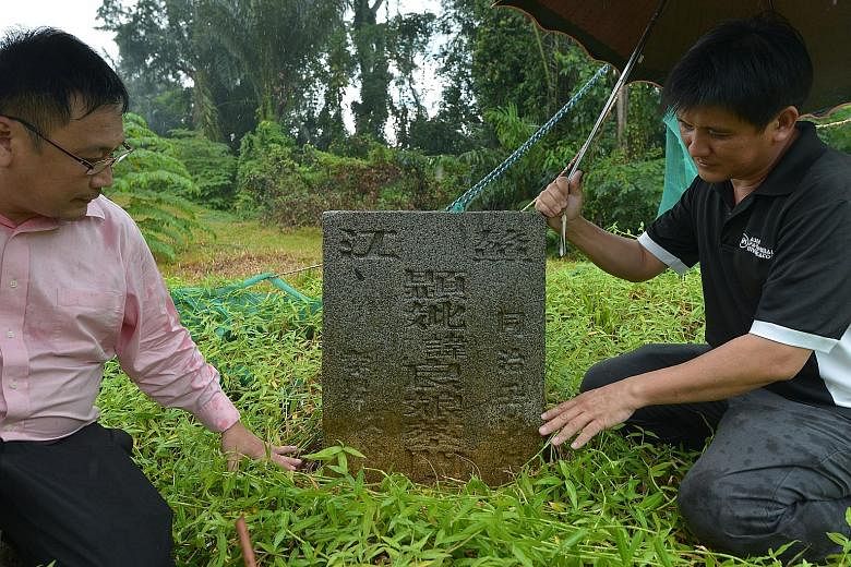 A remnant of the boundary wall (right) of the 129-year-old former lunatic asylum and (far right) "tomb- hunters" Raymond (in pink) and Charles Goh with one of the Chua family tombstones. The structures were found in late 2014.