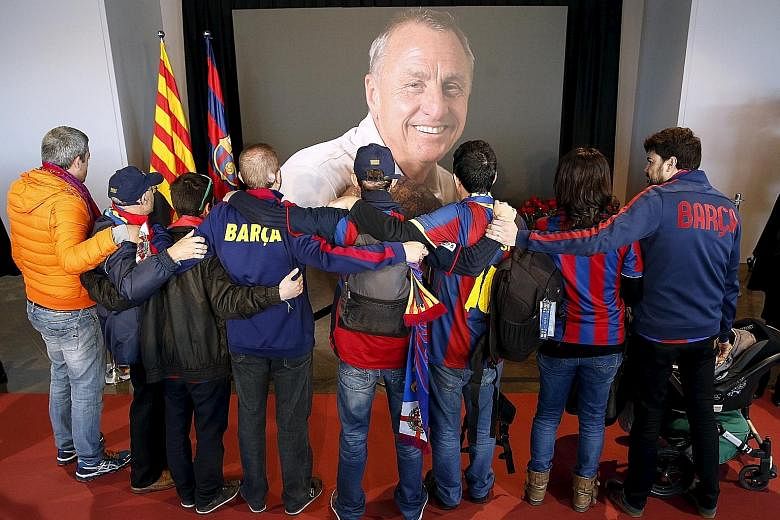 Supporters clad in Barcelona's colours embrace while paying tribute to Dutch legend Johan Cruyff, who won multiple honours with the Catalonian side as player and later, manager.
