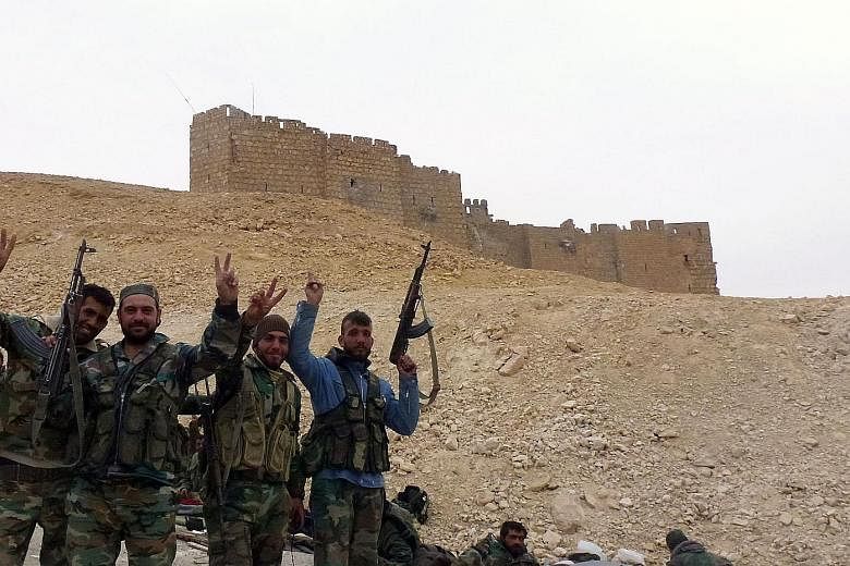 Syrian pro-government forces posing in victory near the ancient Palmyra citadel yesterday. The city is an important symbolic and strategic prize for President Bashar al-Assad's forces, as it provides control of the surrounding desert extending all th